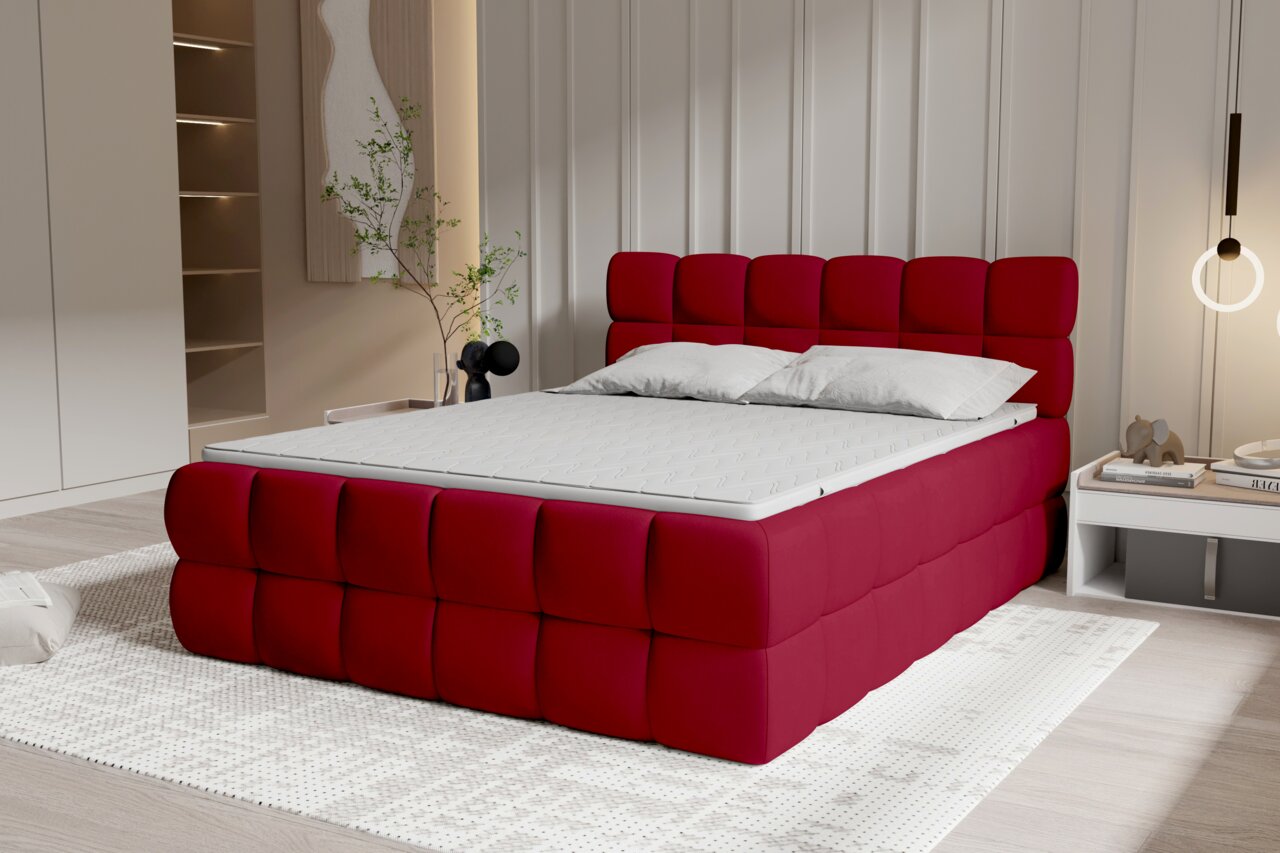 Modernes, gepolstertes Boxspringbett in kräftigem Rot mit quadratisch gestepptem Kopfteil und Bettrahmen, weißer Matratze und zwei Kissen im Schlafzimmer, Ansicht schräg von vorne