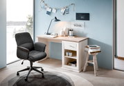 Moderner Schreibtisch in heller Holzoptik mit Schublade und Regal, seitliche Perspektive, dekoriert mit Lampe, Vasen und Büchern, neben einem großen Fenster mit Blick auf verschneite Landschaft.