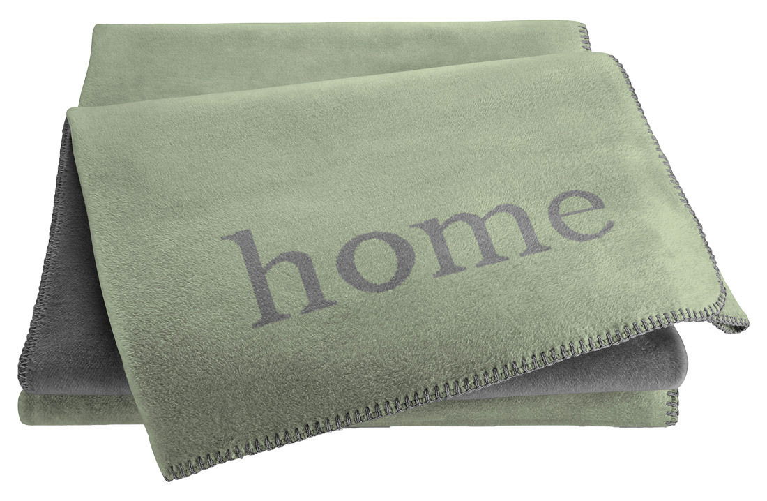 Grüne Wohndecke mit dem Schriftzug 'home', gefaltet und von oben fotografiert.