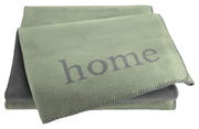 Grüne Wohndecke mit dem Schriftzug 'home', gefaltet und von oben fotografiert.