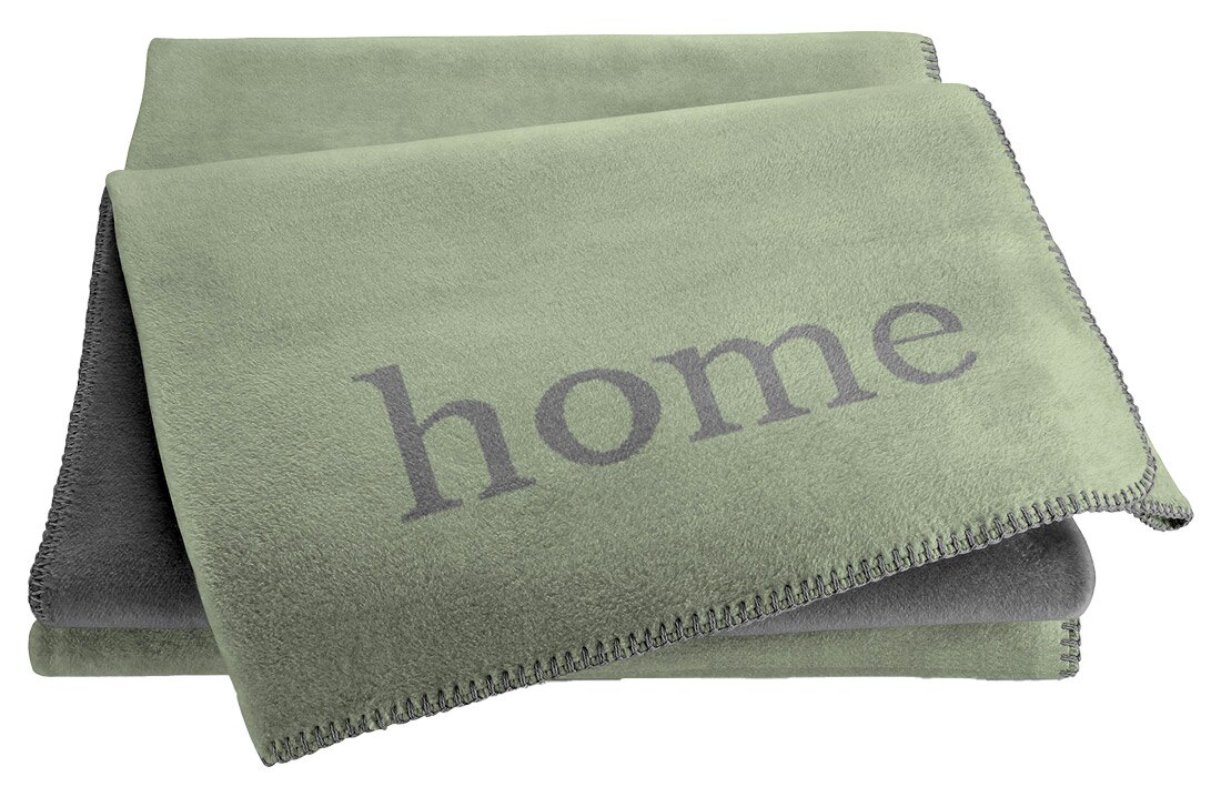 Grüne Wohndecke mit dem Schriftzug 'home', gefaltet und von oben fotografiert.