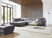 Graues Ecksofa in modernem Wohnzimmer mit Holzverkleidung und großen Fenstern, seitliche Perspektive