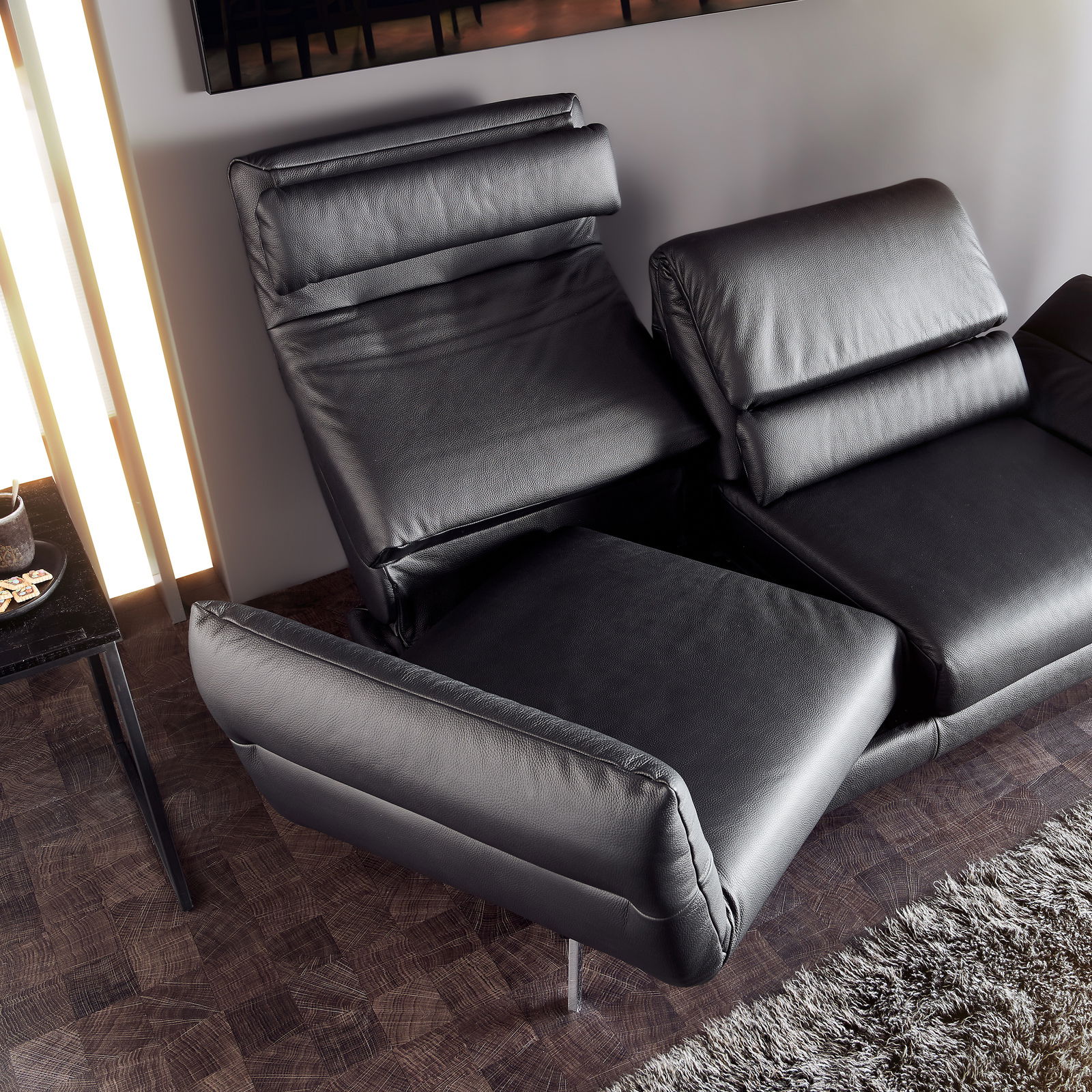Schwarzes 2er-Sofa mit verstellbaren Rückenlehnen und Armlehnen, aus der Vogelperspektive fotografiert.
