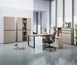 Moderne Büromöbel in einem hellen Raum mit Winkelschreibtisch, Rollcontainer, Aktenschränken und einem ergonomischen Bürostuhl. Perspektive von vorne.