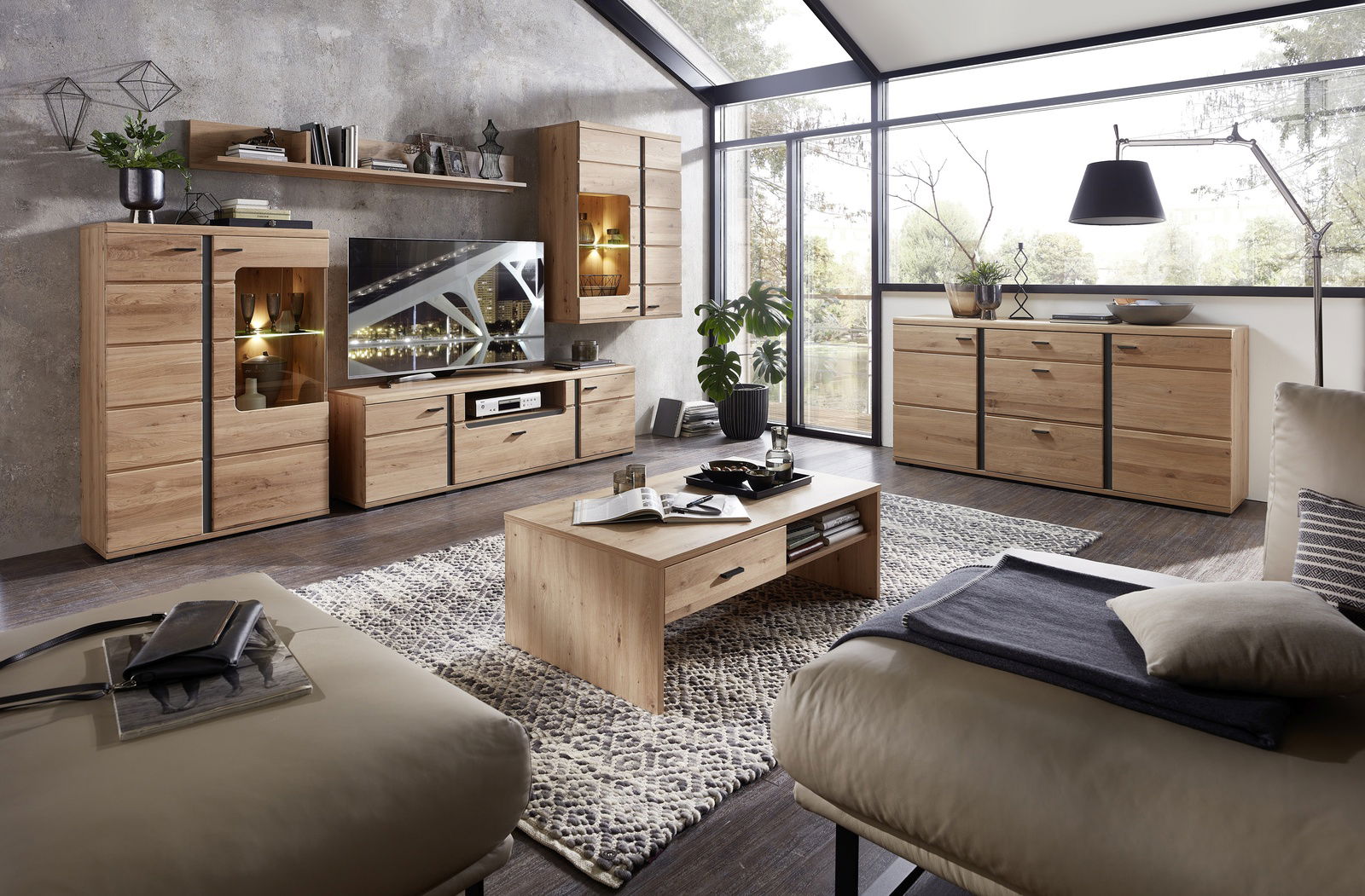 Moderne Wohnzimmermöbel aus Holz, bestehend aus Wohnwand, Sideboard, Vitrine und Couchtisch, in einem hellen Raum mit großen Fenstern, seitliche Perspektive.