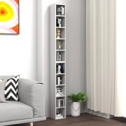 Schmales, hohes weißes Standregal mit mehreren offenen Fächern, dekoriert mit Büchern und Deko, in einer Wohnzimmer-Ecke neben Sofa und Vorhang, Perspektive: frontale Ansicht mit leichter Seitenperspektive von links.