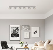 Moderne Deckenstrahler mit sieben verstellbaren Leuchten in einem stilvoll eingerichteten Wohnzimmer, Perspektive von vorne.