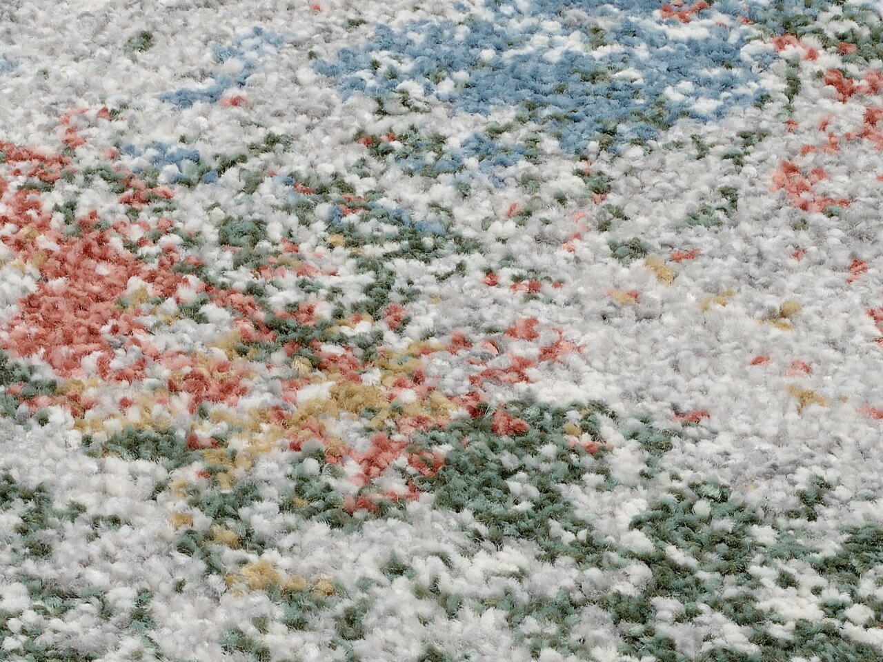 Nahaufnahme eines bunten Frisé-Teppichs mit einer Mischung aus weißen, grünen, roten, blauen und gelben Fasern.
