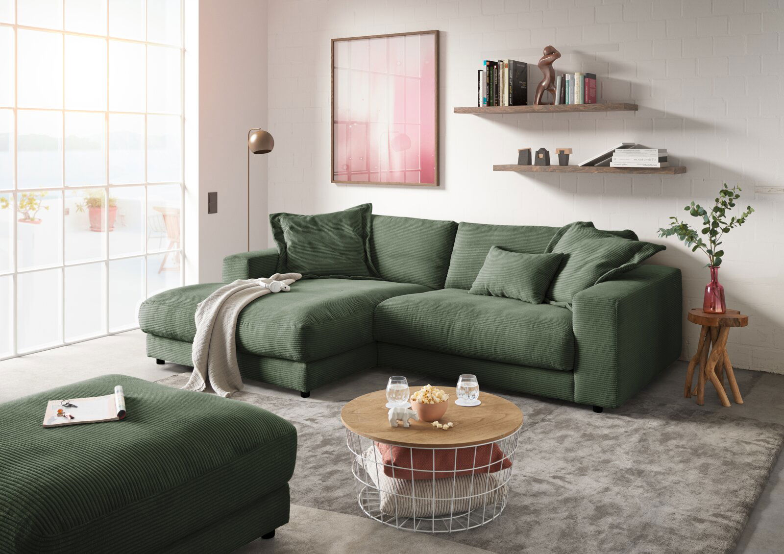 Grüne Longchairkombination in einem modernen Wohnzimmer, fotografiert aus einer leicht seitlichen Perspektive. Die Couch ist mit Kissen dekoriert und steht auf einem grauen Teppich. Ein Couchtisch mit Snacks und Getränken steht davor, umgeben von stilvoll
