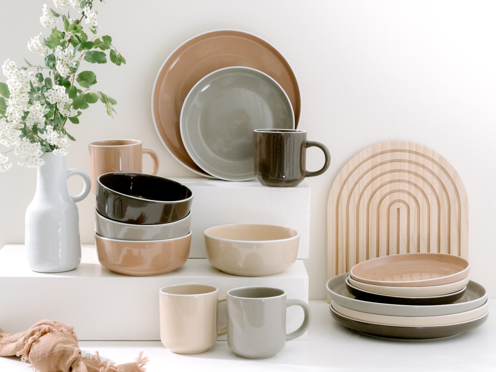 Creatable Kombiservice 16-tlg. NORDIC MOCHA MOUSSE Kombiservice 16-tlg. in neutralen Tönen, bestehend aus Tellern, Schalen und Tassen, stilvoll arrangiert mit Blumen und Holzbrett im Hintergrund, seitliche Perspektive.