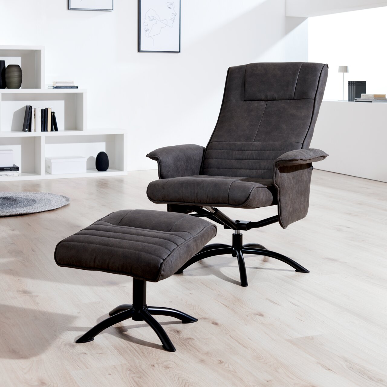 Moderner Relaxsessel mit Hocker in dunklem Stoffbezug, seitliche Perspektive in einem hellen Raum.