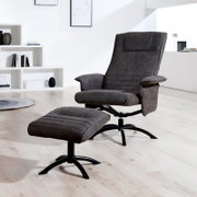 Moderner Relaxsessel mit Hocker in dunklem Stoffbezug, seitliche Perspektive in einem hellen Raum.