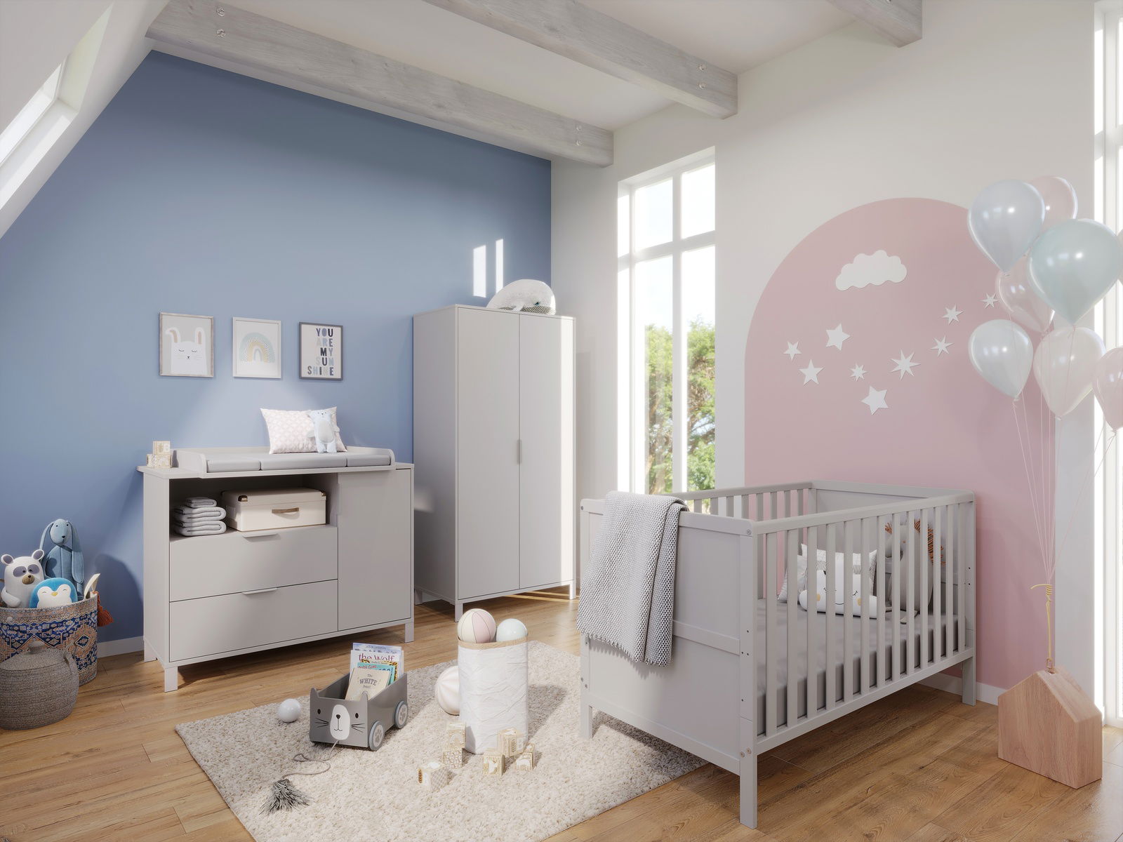 Modernes Babyzimmer mit grauem Gitterbett, Wickelkommode und Kleiderschrank in einem hellen Raum mit blauer und rosa Wand. Perspektive von schräg vorne.