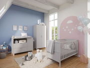 Modernes Babyzimmer mit grauem Gitterbett, Wickelkommode und Kleiderschrank in einem hellen Raum mit blauer und rosa Wand. Perspektive von schräg vorne.