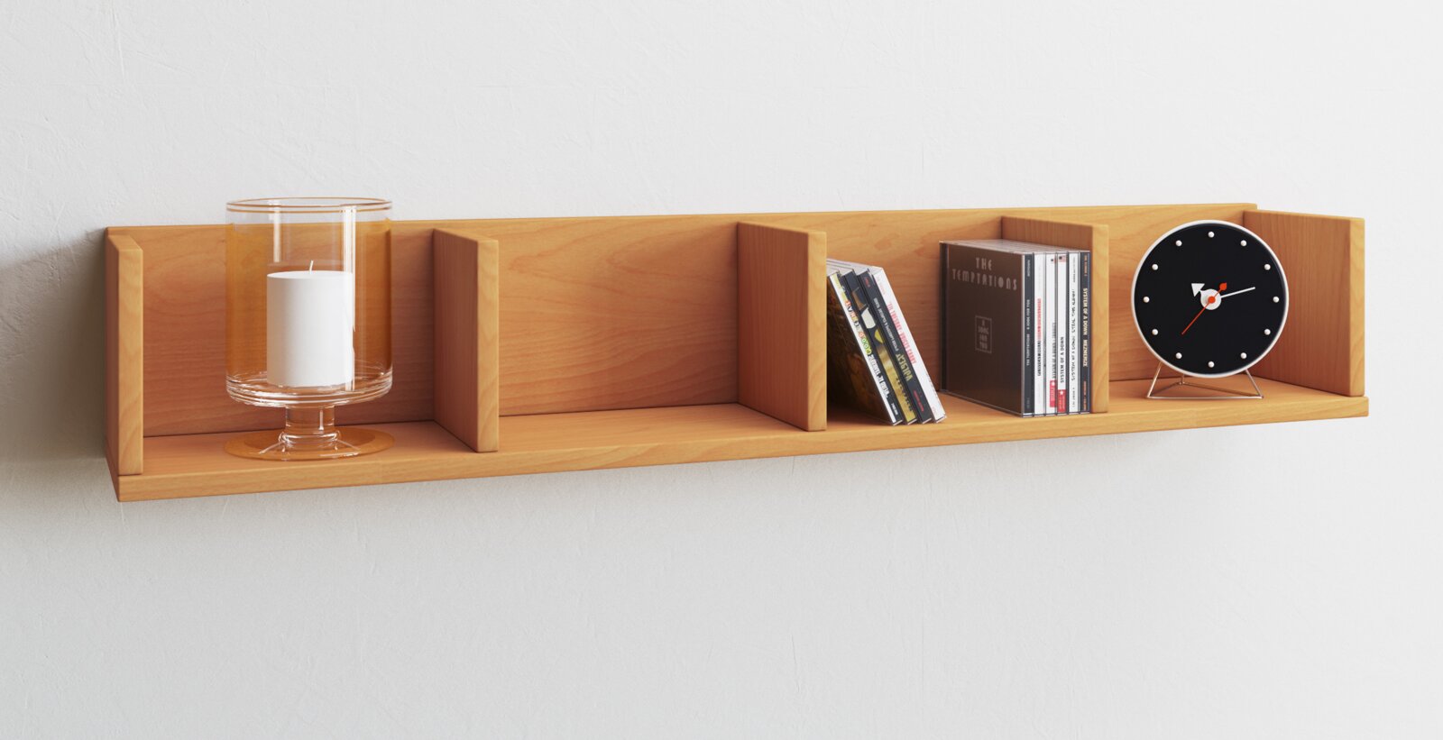 Wandregal aus hellem Holz mit drei Fächern/Trennwänden, dekoriert mit Glas-Windlicht, CDs und schwarzer Tischuhr, frontal aus leichter Seitenperspektive fotografiert