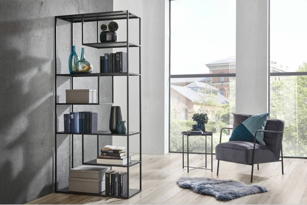 Modernes hohes Regal aus Metall mit mehreren Fächern, dekoriert mit Büchern und Vasen, in einem hellen Raum mit großen Fenstern, seitliche Perspektive.