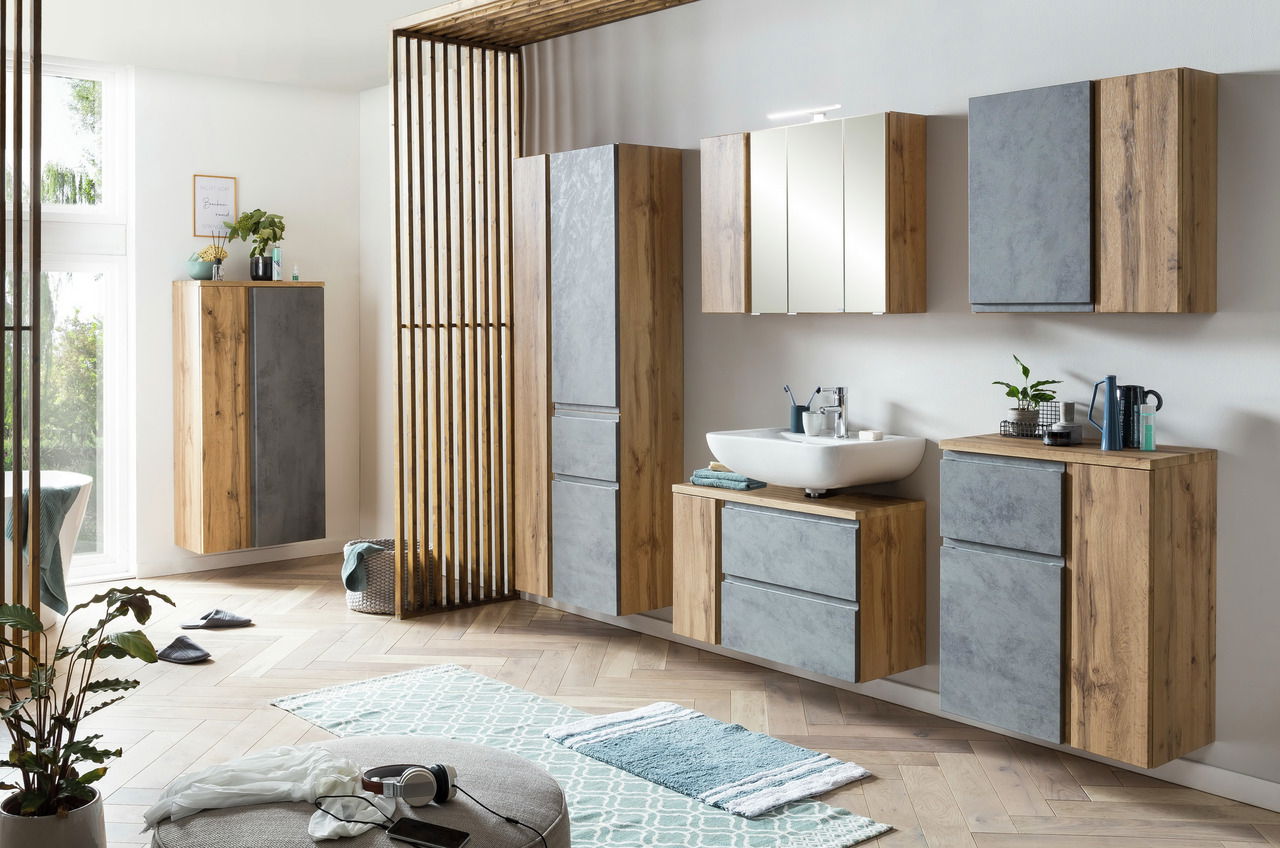 Moderner Waschbeckenunterschrank in Holzoptik mit grauen Fronten, rechts im Badezimmer platziert, aus seitlicher Perspektive fotografiert.