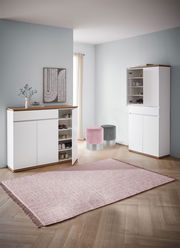 Moderner Eingangsbereich mit zwei weißen Schuhschränken, einem geöffneten, und zwei runden Hockern in Rosa und Grau, aus der Perspektive von vorne.