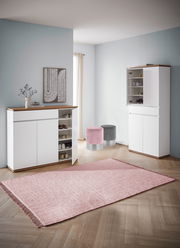 Moderner Eingangsbereich mit zwei weißen Schuhschränken, einem geöffneten, und zwei runden Hockern in Rosa und Grau, aus der Perspektive von vorne.