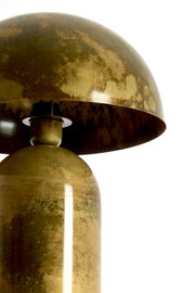 Close-up vanuit laag perspectief van een vintage tafellamp in verweerd messing met koepelvormige kap tegen een witte achtergrond