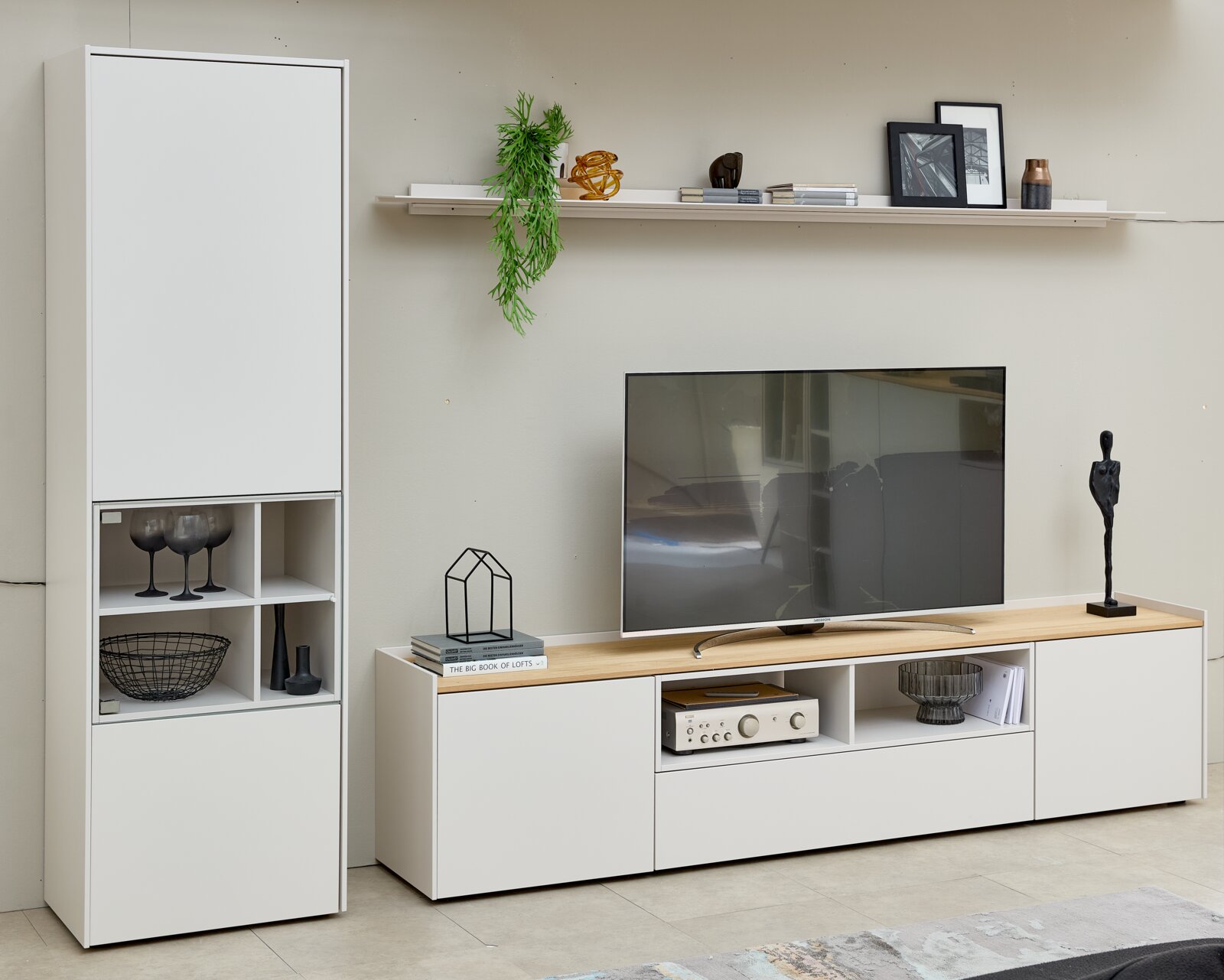 Modern wit tv-meubel en hoge vitrinekast met open vakken en houten blad, vanuit schuin vooraanzicht in een stijlvol ingerichte woonkamer