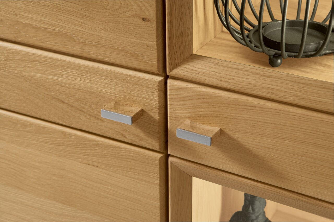 Close-up van een wandmeubel van hout met moderne metalen handgrepen, zijaanzicht