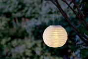 Hängende Solarleuchte in Form einer Papierlaterne, beleuchtet und an einem Baum befestigt, seitliche Perspektive