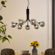 Moderne Hängeleuchte mit mehreren kugelförmigen Glühbirnen, von unten betrachtet, über einem Esstisch mit Sonnenblumen.