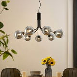 Moderne Hängeleuchte mit mehreren kugelförmigen Glühbirnen, von unten betrachtet, über einem Esstisch mit Sonnenblumen.