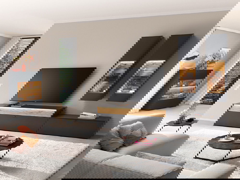Ein modernes Wohnzimmer mit hellem Sofa, dunklen Möbeln, dekorativer Beleuchtung und großem Fernseher.