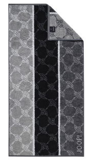 Handtuch mit geometrischem Muster in Grautönen, von oben fotografiert.