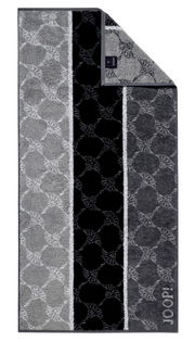 Handtuch mit geometrischem Muster in Grautönen, von oben fotografiert.