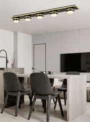 Moderne LED-Deckenleuchte mit fünf runden Leuchtkörpern in einem eleganten Esszimmer, Perspektive von unten.