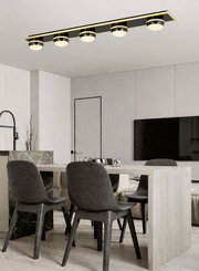 Moderne LED-Deckenleuchte mit fünf runden Leuchtkörpern in einem eleganten Esszimmer, Perspektive von unten.