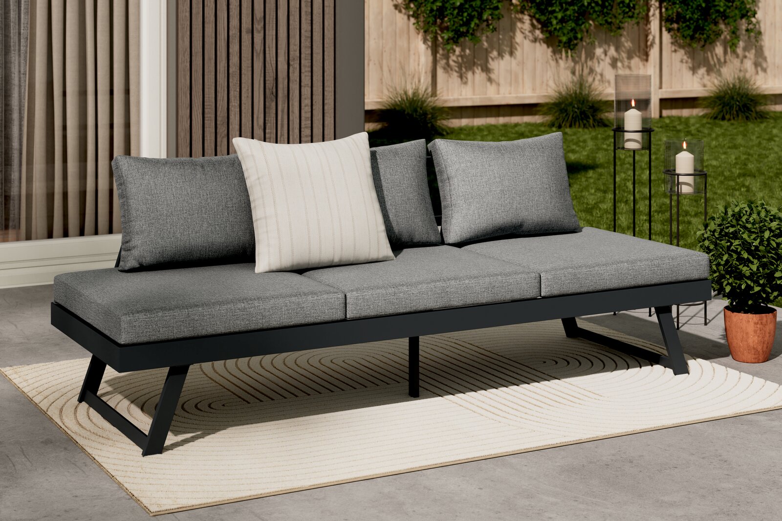 Modernes Lounge-Sofa in Grau mit drei Kissen, auf einer Terrasse mit Blick von vorne.