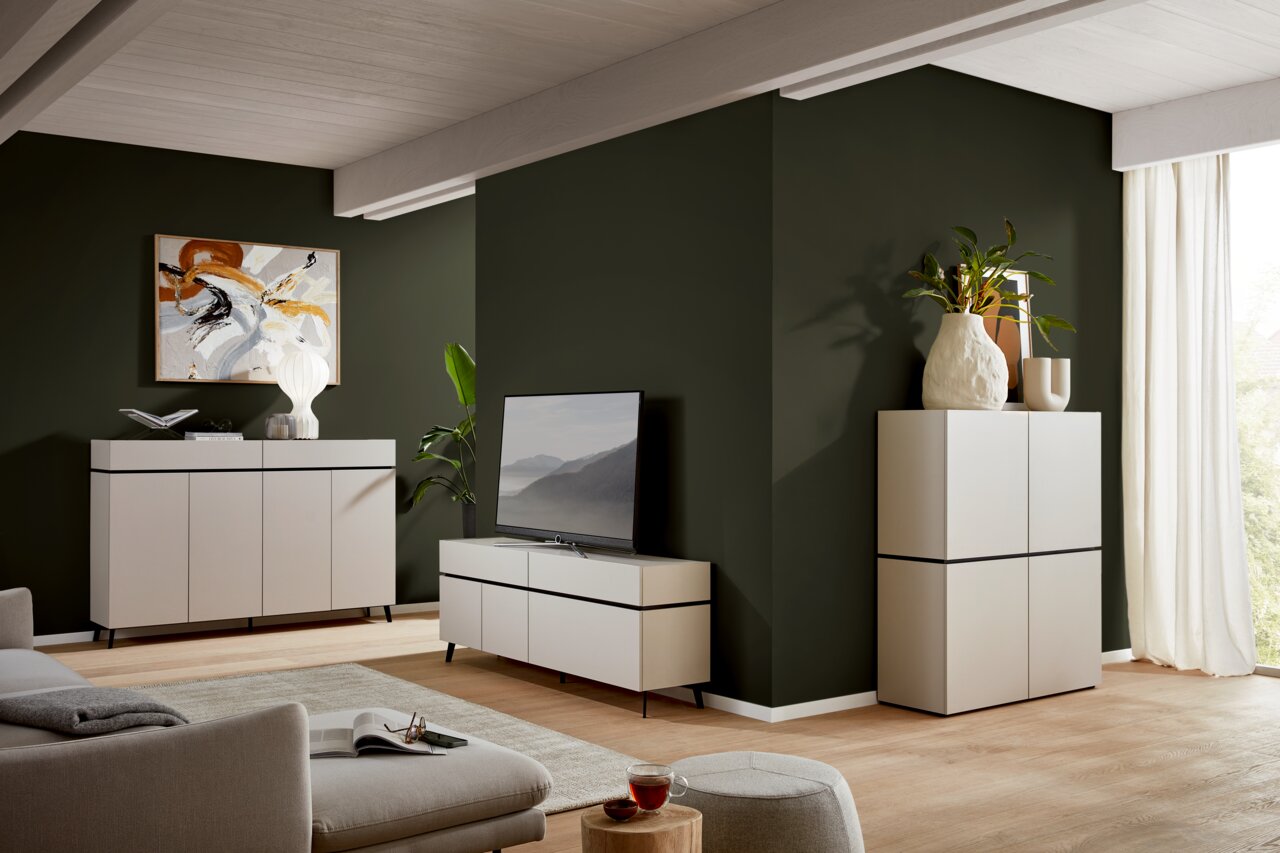Voleo Sideboard UNIQUE Modernes Wohnzimmer mit TV-Lowboard, Sideboard und Highboard in heller Holzoptik, seitliche Perspektive.