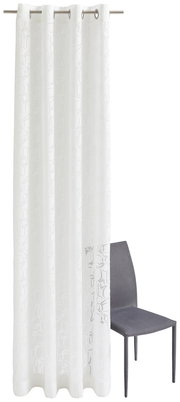 Weiße Vorhang mit Ösen und feinem Ornamentmuster, frontal fotografiert neben einem grauen Stuhl