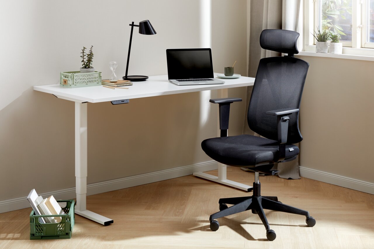 E-Serie E-Schreibtisch E-FLEX Moderner E-Schreibtisch in einem hellen Raum, ausgestattet mit einem Laptop, einer Lampe und Pflanzen, seitliche Perspektive.