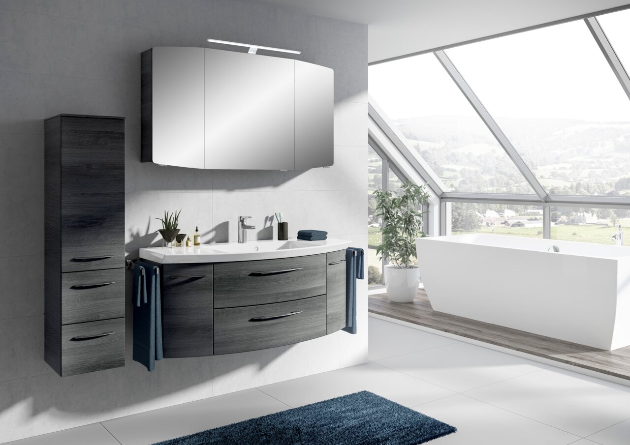 Moderne Badkombination mit Waschbecken, Spiegel und Schrank in einem hellen Badezimmer mit Panoramafenster, seitliche Perspektive