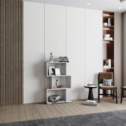 Modernes Wohnraum-Setup mit weißem, asymmetrischem Regal mit Dekoration vor hellen, grifflosen Schrankfronten; Perspektive: frontale Ansicht auf Augenhöhe.