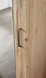 Nahaufnahme eines Garderobenschranks mit Holzmaserung und Metallgriff, seitliche Perspektive