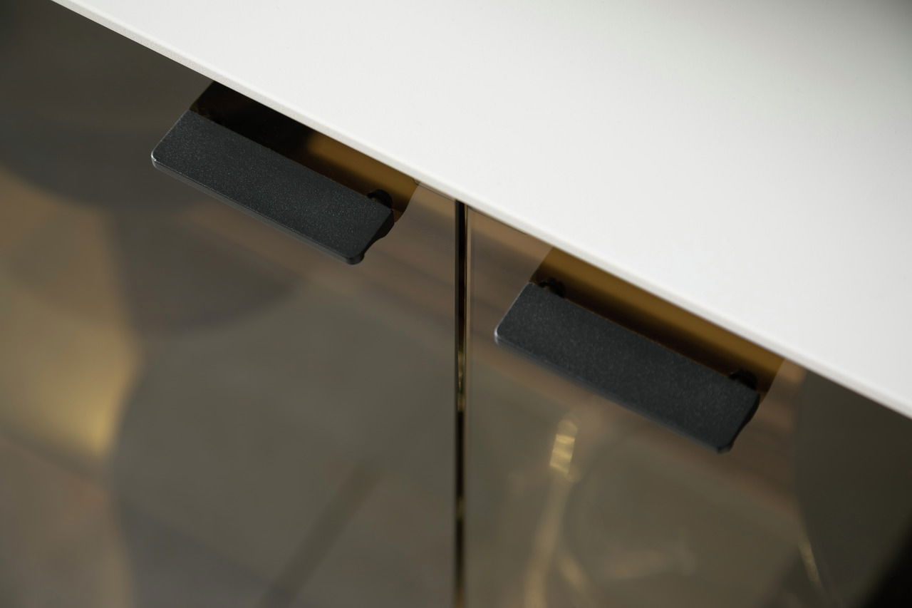 Nahaufnahme eines Sideboards mit weißer Oberfläche und schwarzen Griffen, von oben betrachtet.