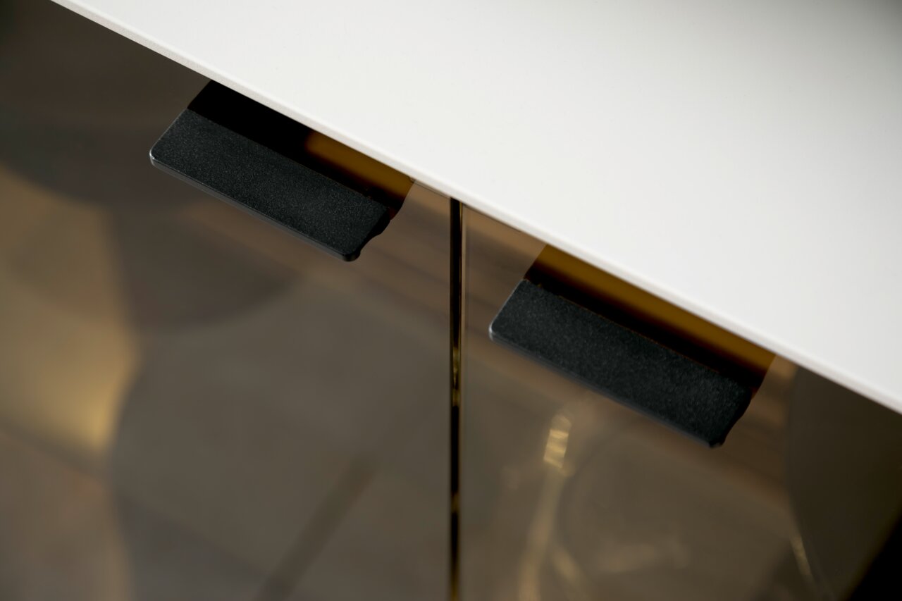 Nahaufnahme eines Sideboards mit weißer Oberfläche und schwarzen Griffen, von oben betrachtet.