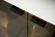 Close-up van een dressoir met een wit oppervlak en zwarte handgrepen, gezien van bovenaf.