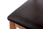 Nahaufnahme eines Stuhlsitzes mit schwarzem Lederbezug und Holzgestell, von oben betrachtet.