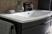 Nahaufnahme einer modernen Badkombination mit weißem Waschbecken und schwarzem Unterschrank, seitliche Perspektive.