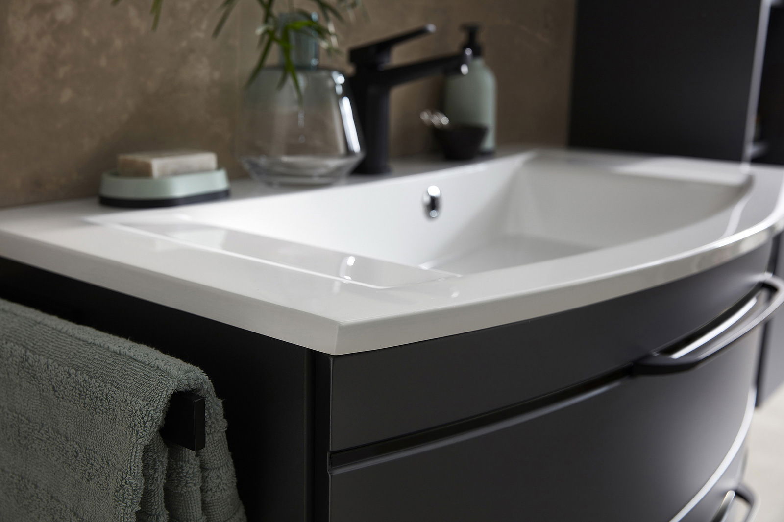 Nahaufnahme einer modernen Badkombination mit weißem Waschbecken und schwarzem Unterschrank, seitliche Perspektive.