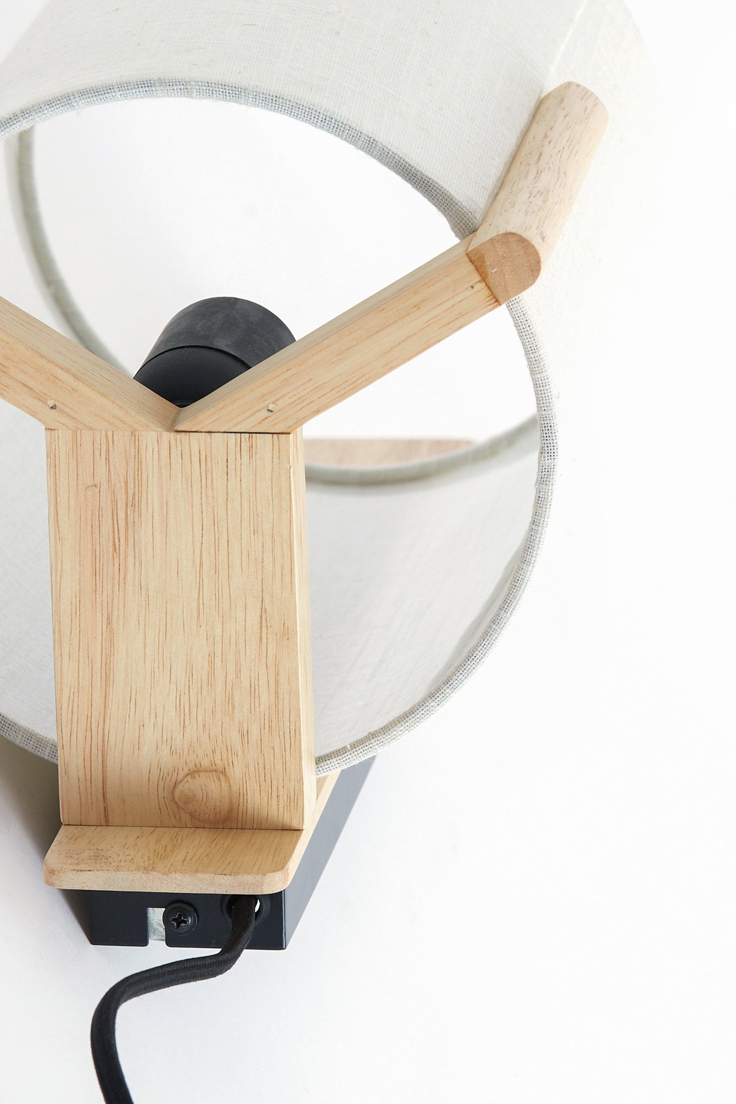 Nahaufnahme einer modernen Wandleuchte mit Holzdetails und einem weißen Stoffschirm, von oben betrachtet.