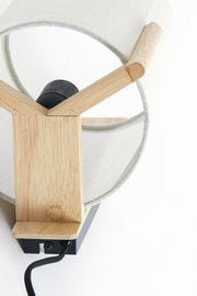 Nahaufnahme einer modernen Wandleuchte mit Holzdetails und einem weißen Stoffschirm, von oben betrachtet.