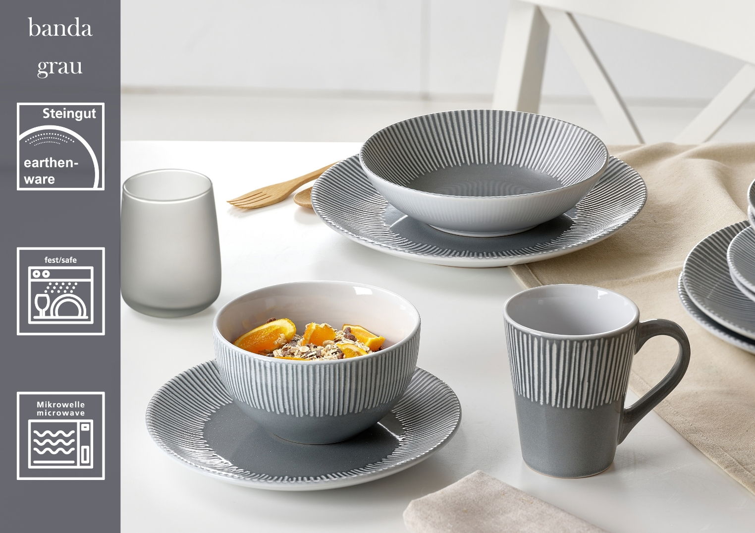 Graues 18-teiliges Tellerset aus Steingut mit modernem Rillenmuster, bestehend aus Tellern, Schalen und Tassen, auf einem Tisch arrangiert. Perspektive von oben.